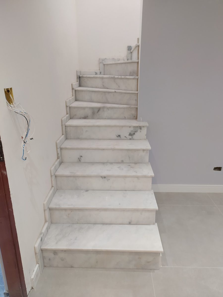 Escada revestida em mármore branco durante a obra