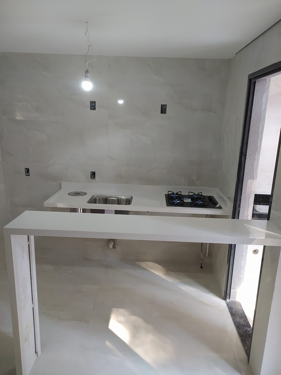 Bancada clara com cooktop embutido e parede em porcelanato marmorizado