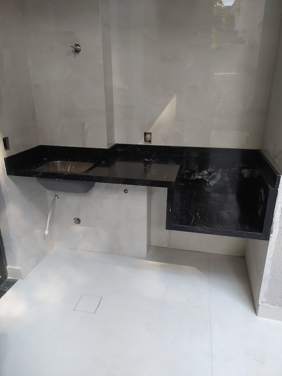 Bancada em granito preto em formato de L instalada em área de serviço