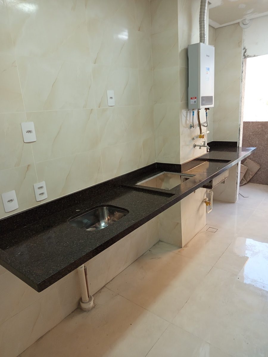 Bancada longa em granito preto com cuba de inox e revestimento bege